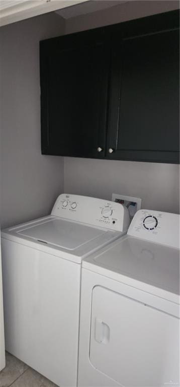 clothes washing area with cabinets, light tile patterned flooring, and washing machine and dryer