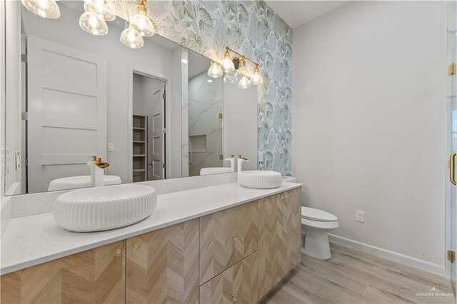 bathroom with hardwood / wood-style floors, vanity, toilet, and walk in shower