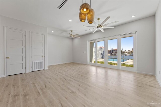 unfurnished room featuring ceiling fan, a water view, and light wood-type flooring