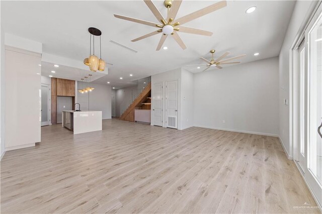 unfurnished living room featuring ceiling fan, light wood-type flooring, and sink