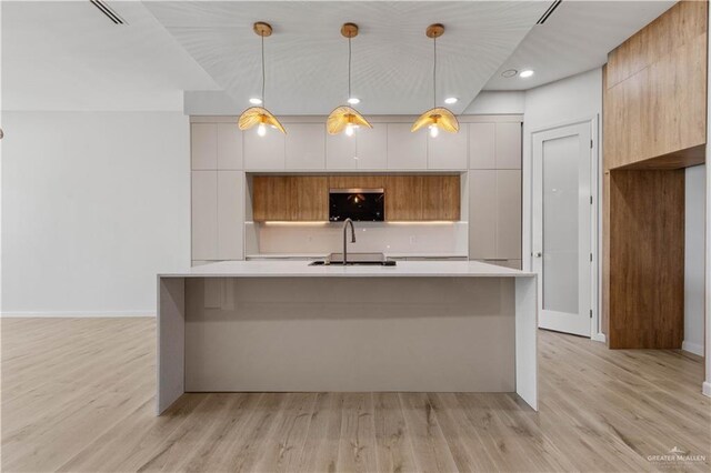 kitchen featuring white cabinets, light hardwood / wood-style flooring, and hanging light fixtures