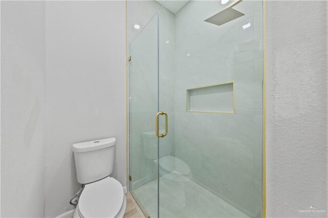 bathroom featuring hardwood / wood-style flooring, an enclosed shower, and toilet