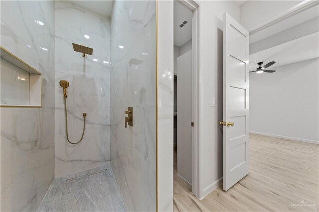 bathroom featuring hardwood / wood-style floors, ceiling fan, and a tile shower