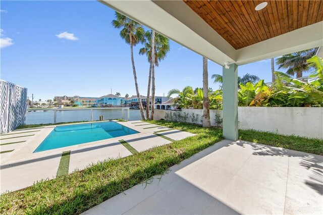 view of pool featuring a water view and a patio