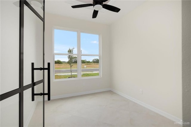 empty room with ceiling fan and baseboards