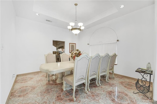 tiled dining space featuring a tray ceiling and an inviting chandelier