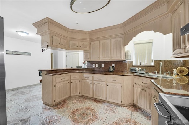 kitchen with kitchen peninsula, sink, stainless steel range, and tasteful backsplash