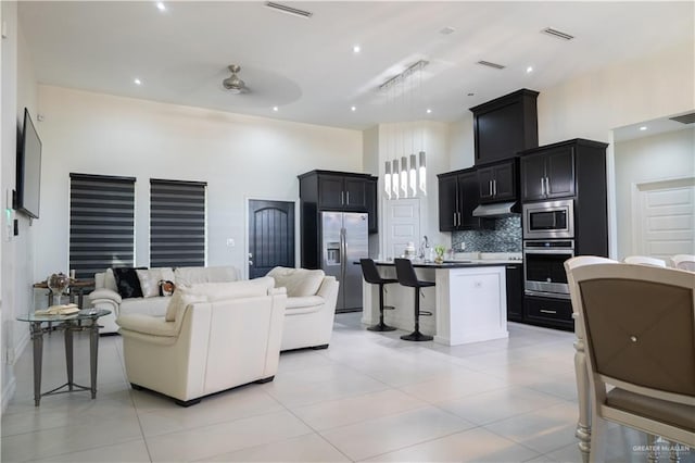 living area with light tile patterned flooring, visible vents, and a towering ceiling