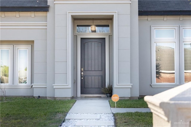 doorway to property with roof with shingles and stucco siding