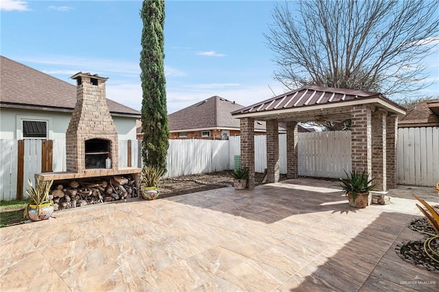 view of patio / terrace featuring an outdoor brick fireplace and a gazebo