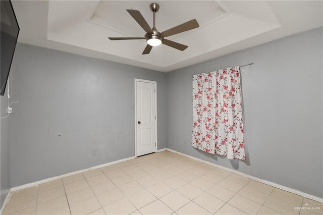 unfurnished room with light tile patterned flooring, ceiling fan, and a tray ceiling