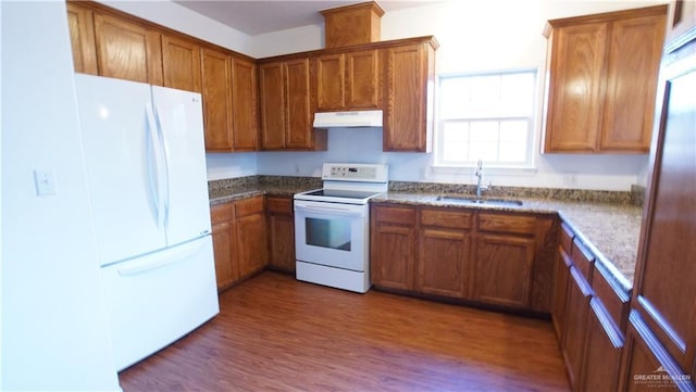 2141 Diaz Ave, Mcallen, TX 78503 - kitchen with white appliances, under cabinet range hood, brown cabinets, and wood finished floors