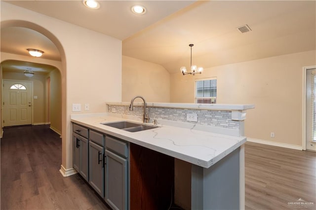 3707 Alvarado St, Edinburg, TX 78539 - kitchen with gray cabinetry, backsplash, dark wood-type flooring, light stone counters, and a chandelier