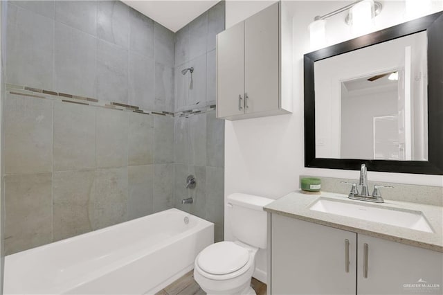 full bathroom with vanity, toilet, tiled shower / bath, and ceiling fan