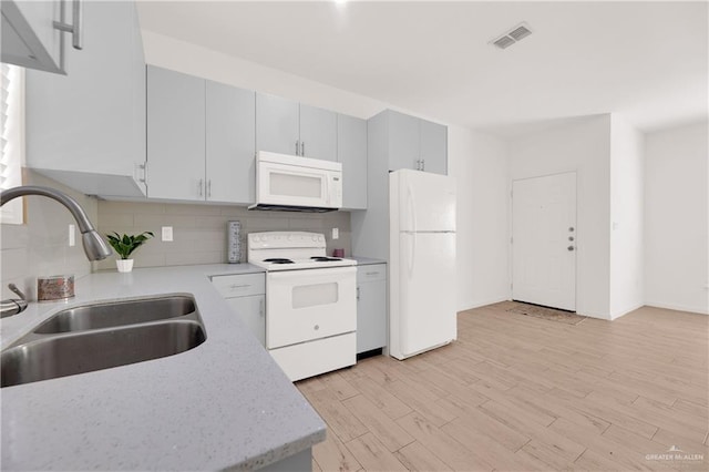 kitchen featuring sink, tasteful backsplash, light stone counters, white appliances, and light wood-type flooring