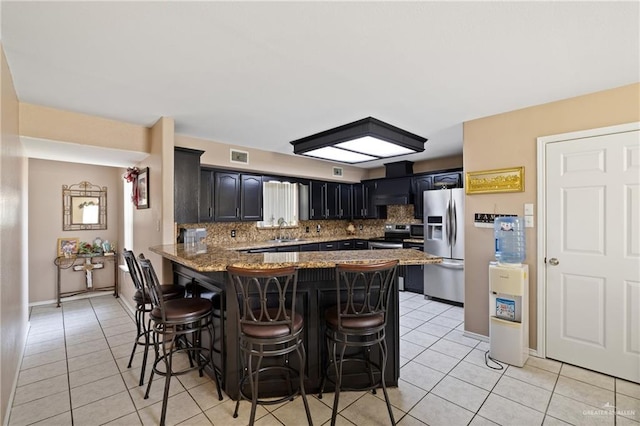 2315 E Sprague St, Edinburg, TX 78542 - kitchen with a peninsula, stainless steel appliances, light tile patterned flooring, a breakfast bar area, and backsplash