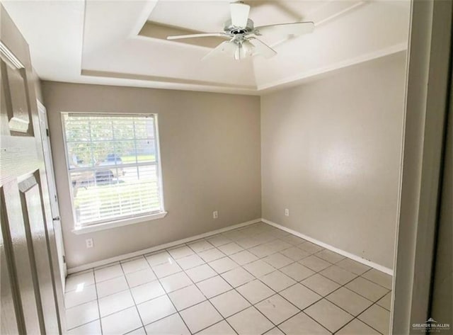 empty room featuring a ceiling fan, a raised ceiling, and light tile patterned floors