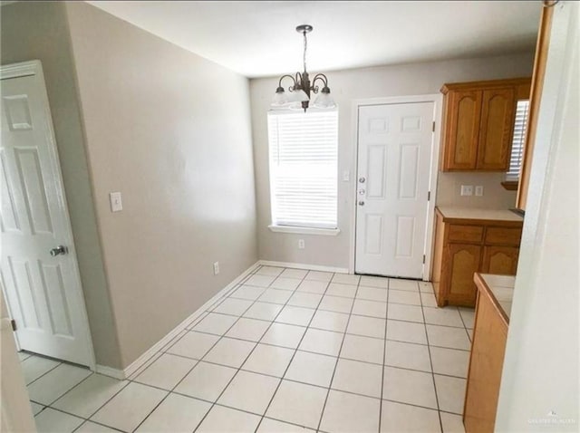 unfurnished dining area with a chandelier, baseboards, and light tile patterned floors