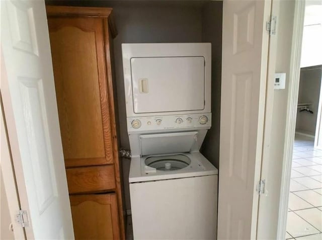 laundry room with stacked washer and dryer, light tile patterned floors, and laundry area