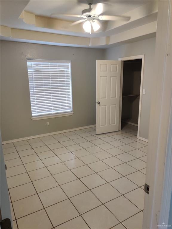 unfurnished room featuring light tile patterned floors, ceiling fan, baseboards, and a raised ceiling