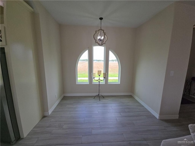 spare room featuring light wood-type flooring and an inviting chandelier