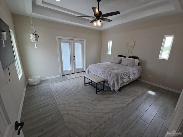 bedroom featuring access to outside, a raised ceiling, and dark wood-type flooring