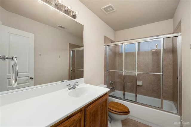 full bathroom with shower / bath combination with glass door, tile patterned flooring, vanity, and toilet