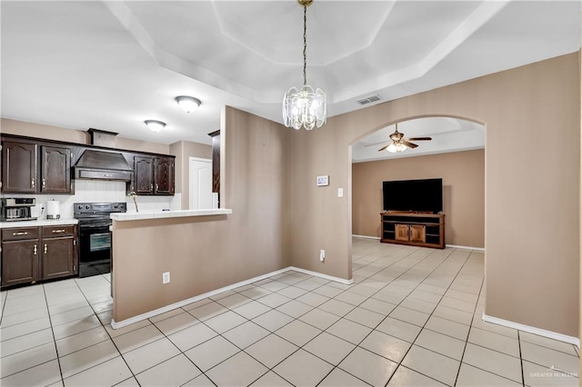 kitchen featuring dark brown cabinetry, light tile patterned floors, electric range, a tray ceiling, and range hood