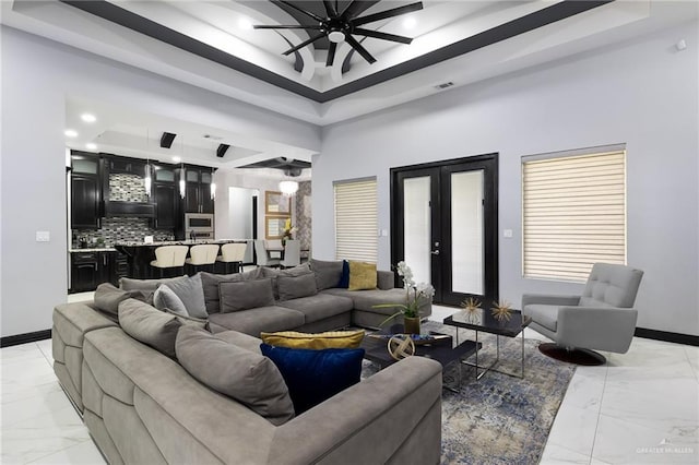 living room with a tray ceiling, ceiling fan, and french doors