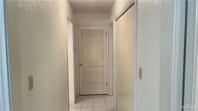 corridor with light tile patterned flooring and a textured ceiling