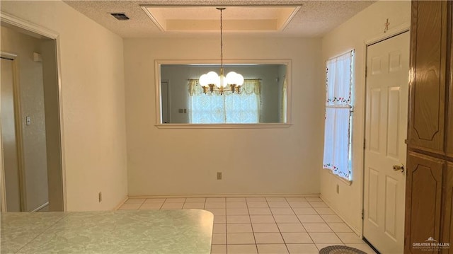 unfurnished dining area with light tile patterned floors, a textured ceiling, and a notable chandelier