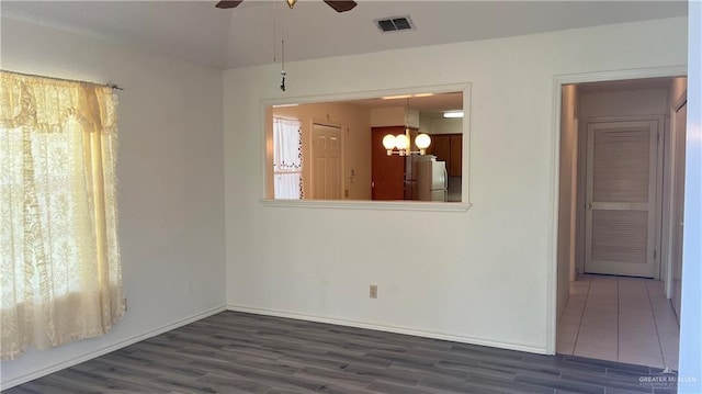 spare room featuring ceiling fan with notable chandelier and dark hardwood / wood-style flooring