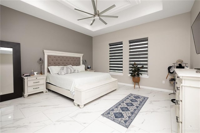 bedroom featuring baseboards, marble finish floor, a tray ceiling, and ceiling fan
