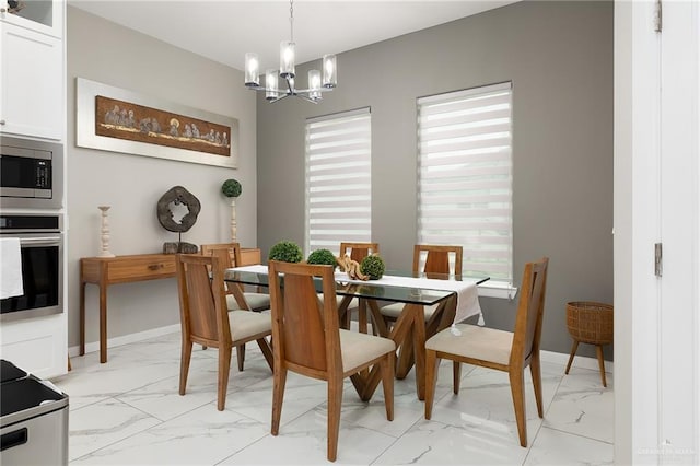 dining area with marble finish floor, plenty of natural light, and an inviting chandelier