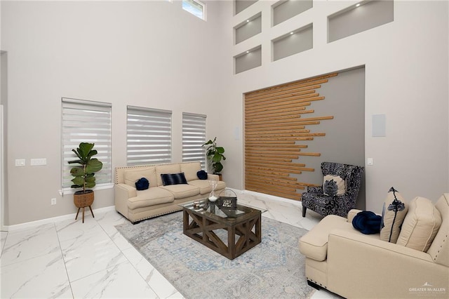 living room with baseboards, marble finish floor, and a high ceiling