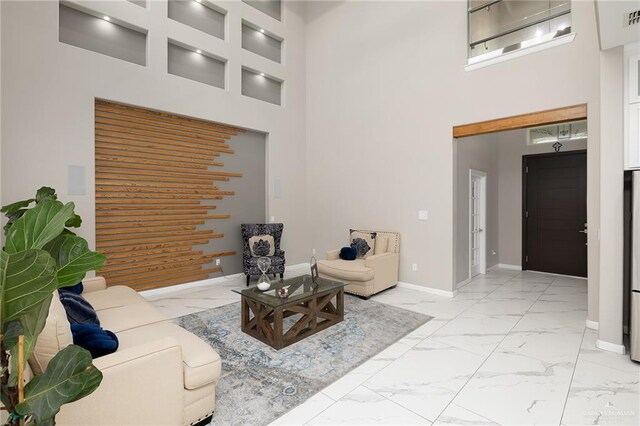 living area featuring baseboards, marble finish floor, visible vents, and a high ceiling