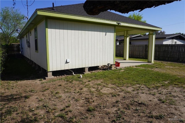 view of home's exterior featuring roof with shingles, a patio area, and fence