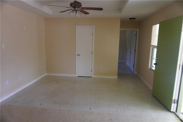 unfurnished room with baseboards, a tray ceiling, and tile patterned floors