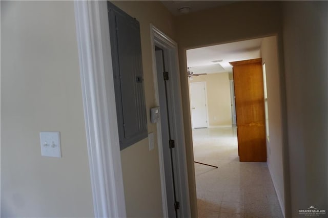 hallway with baseboards, electric panel, and light floors