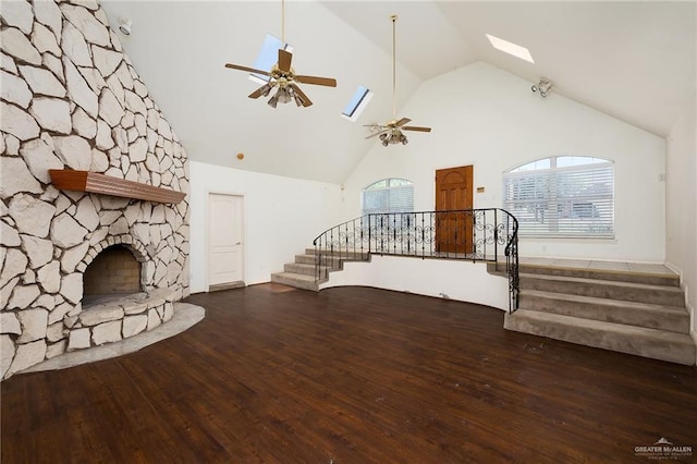 unfurnished living room featuring a skylight, ceiling fan, a stone fireplace, high vaulted ceiling, and hardwood / wood-style floors