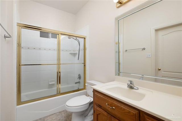 full bathroom with combined bath / shower with glass door, vanity, tile patterned flooring, and toilet