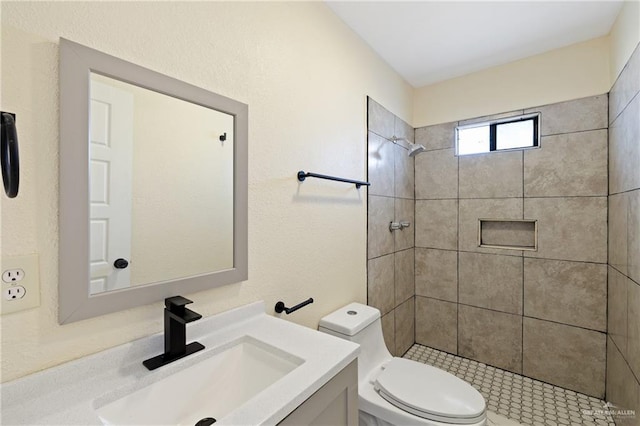 bathroom featuring vanity, tiled shower, and toilet