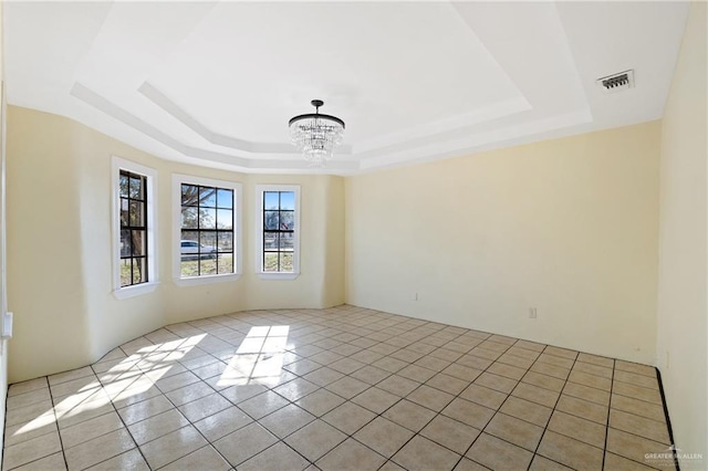 spare room with an inviting chandelier and a tray ceiling