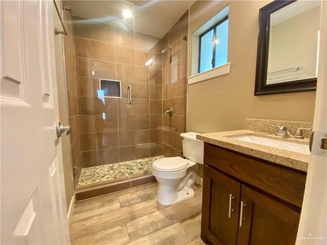 bathroom featuring a shower with door, toilet, and vanity