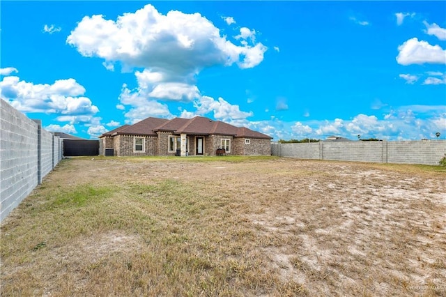 back of property featuring a yard and a fenced backyard