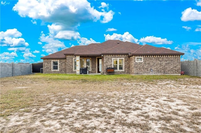 back of property featuring a fenced backyard, brick siding, and a yard