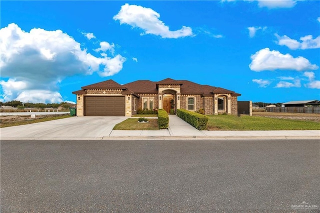 mediterranean / spanish-style house featuring an attached garage, a front lawn, and concrete driveway
