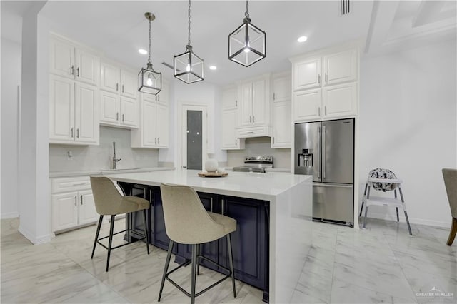 kitchen with under cabinet range hood, marble finish floor, appliances with stainless steel finishes, and a center island