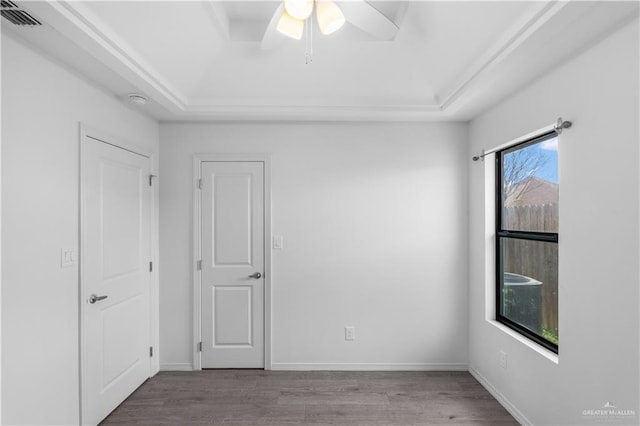 unfurnished room featuring light wood finished floors, baseboards, visible vents, and a raised ceiling