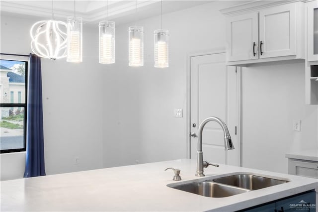 kitchen featuring light countertops, a sink, white cabinetry, and decorative light fixtures